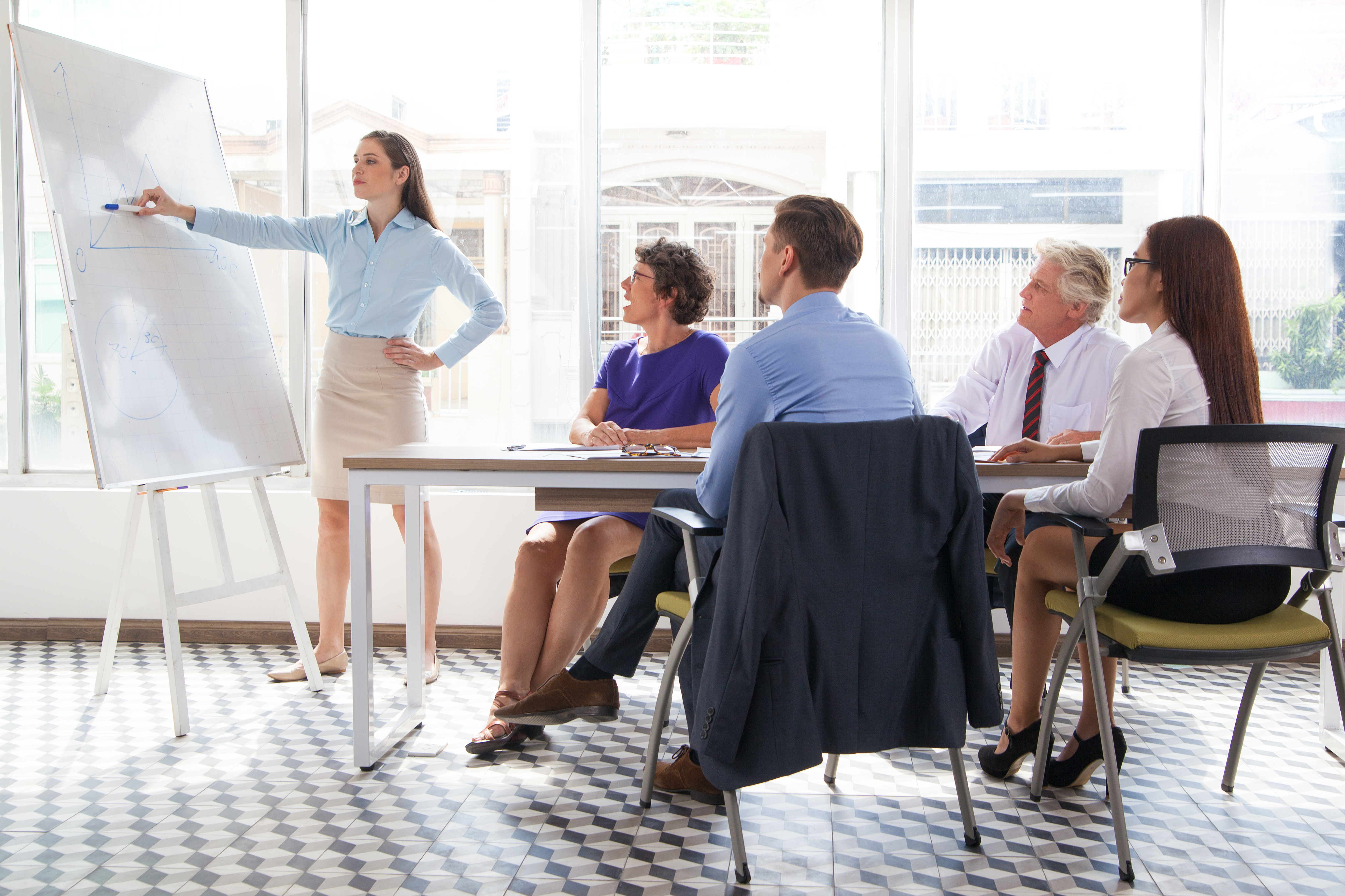 Female business coach explaining graph at meeting.